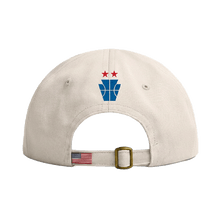 Load image into Gallery viewer, Beige cap with blue and red logo, adjustable strap featuring small American flag patch and brass buckle.
